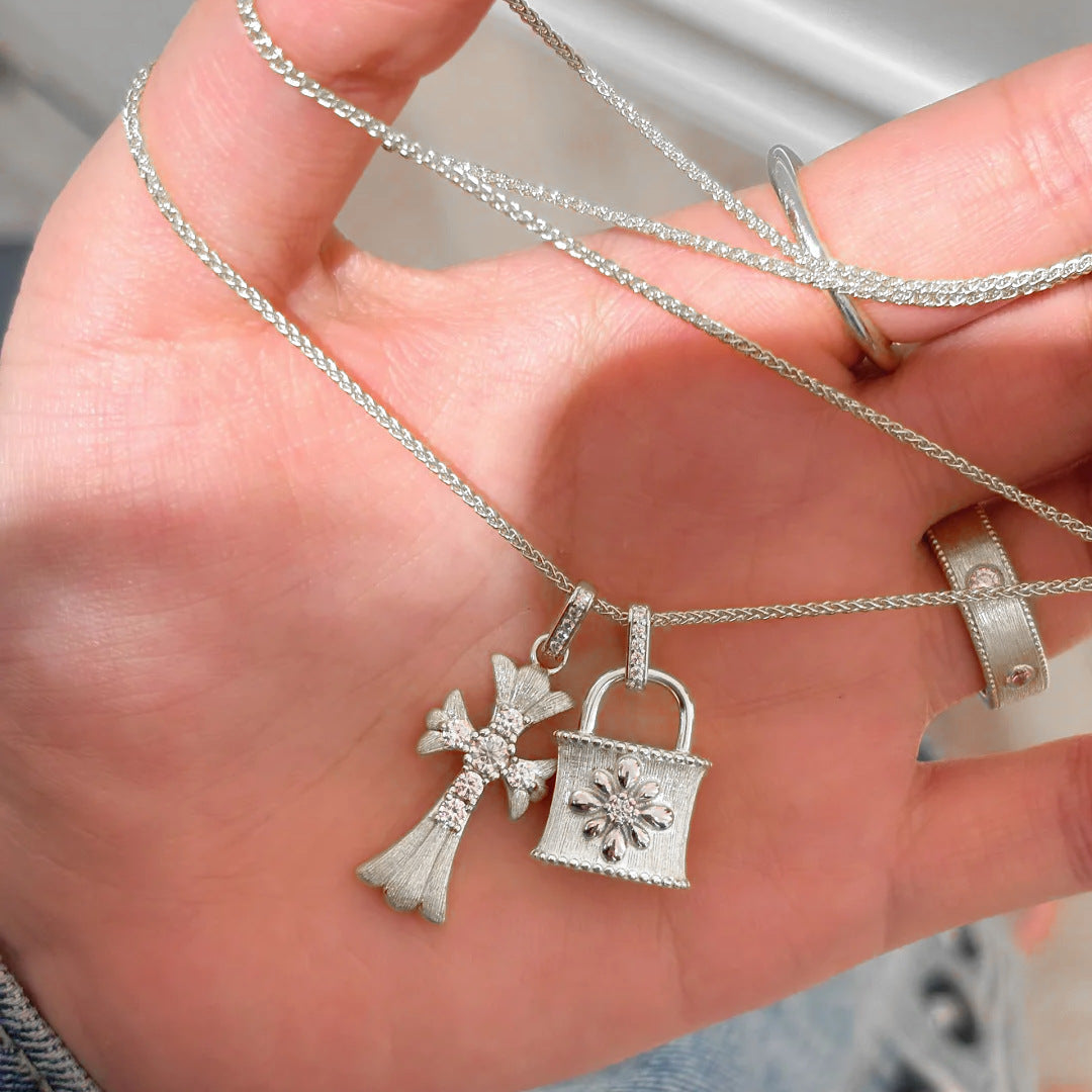 Cross-shaped brushed silver necklace with diamond accents